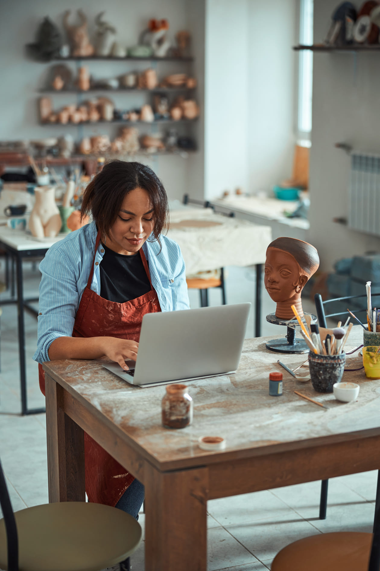 Ceramic artist working on her laptop in a pottery studio