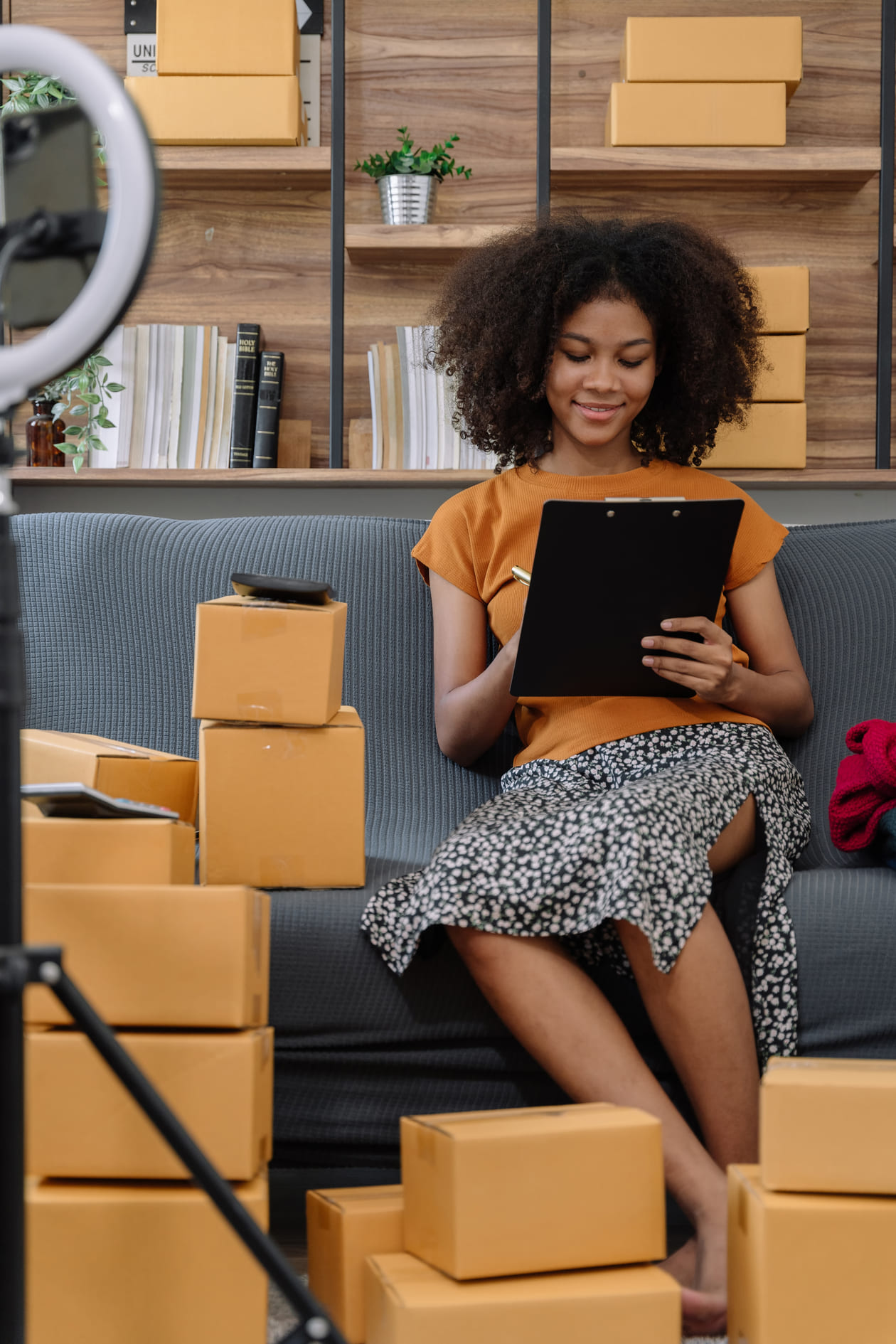 Small business owner checking orders on a tablet among parcels