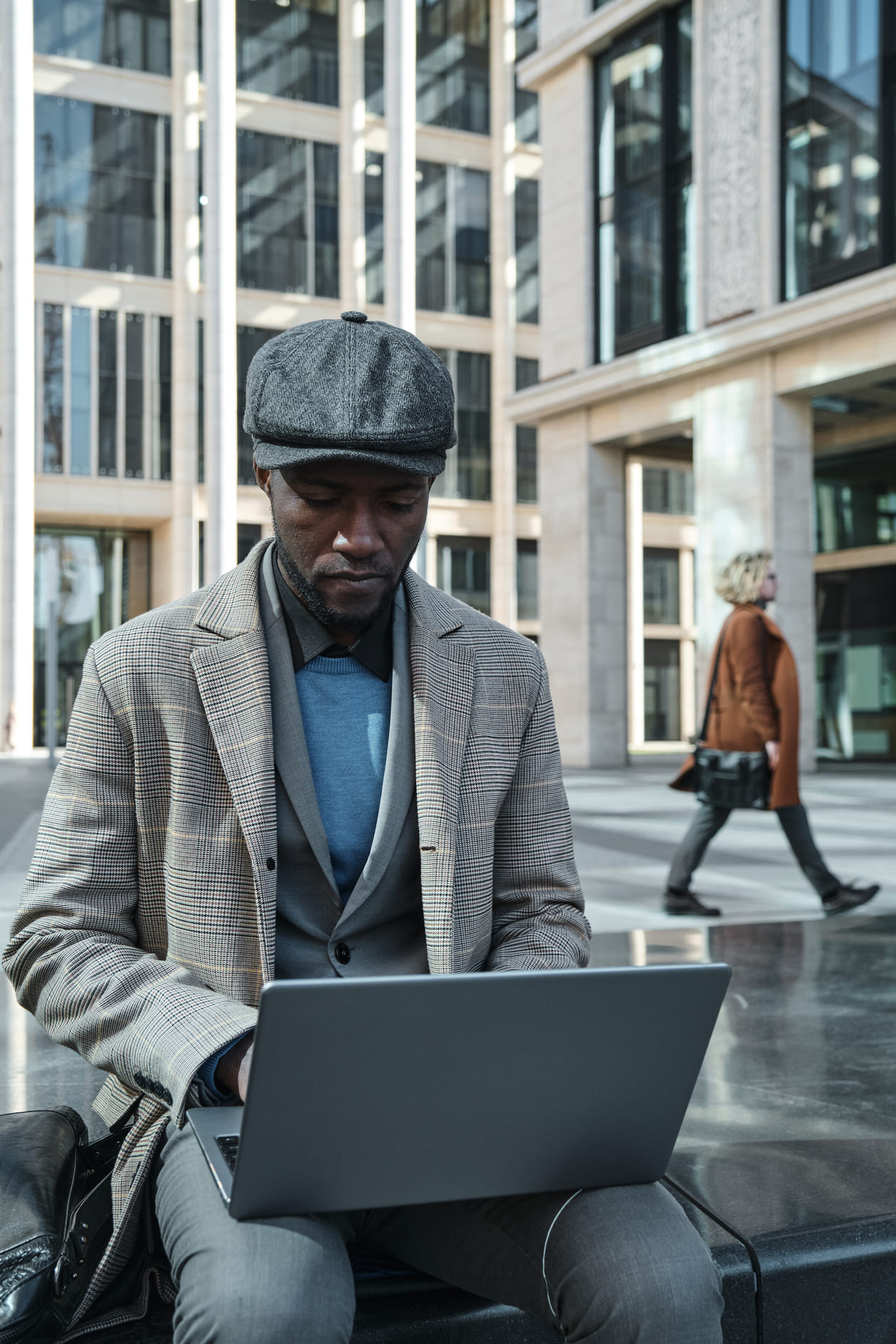 Designer in a cap working on a laptop outdoors